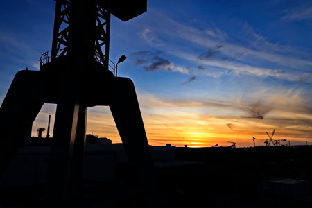 Silhouette of crane in port at sunset. Industrial background.の写真素材