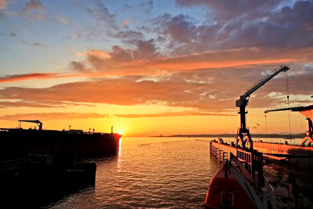 Bulk cargo ship under port crane bridge at sunset, Odessa, Ukraine