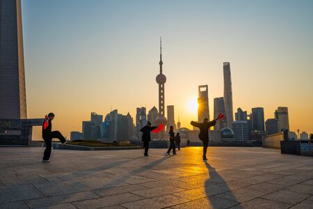 Shanghai, China - February 6, 2018: People playing Tai Chi on the Bund at sunrise, Oriental Pearl Tower and other famous skyscraper on background, in Shanghai, China. One of the Top Ten Shanghai Attractions.のeditorial素材
