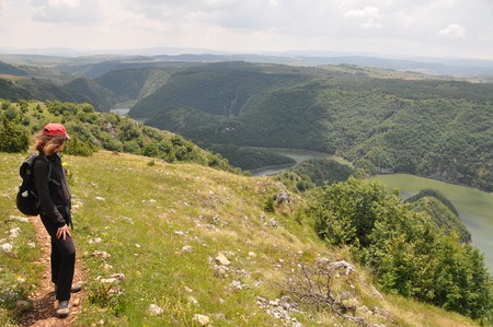 Young woman hiking in nature and looking the scenic view of River Uvac on a sunny summer dayの写真素材
