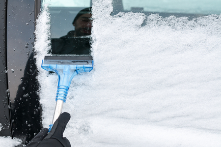 Man Cleaning Car Window From Snow and Iceの写真素材