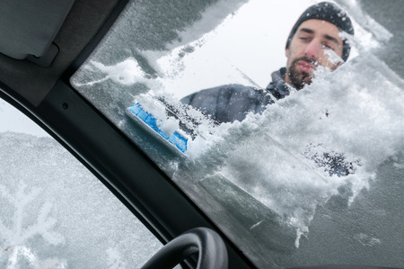 Man Cleaning Car Windshield From Snow and Iceの写真素材