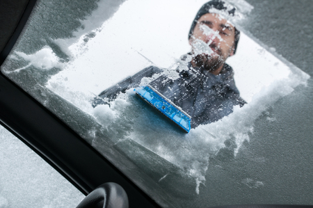Man Cleaning Car Windshield From Snow and Iceの写真素材