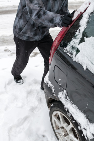 Man pushing car stuck in snowの写真素材