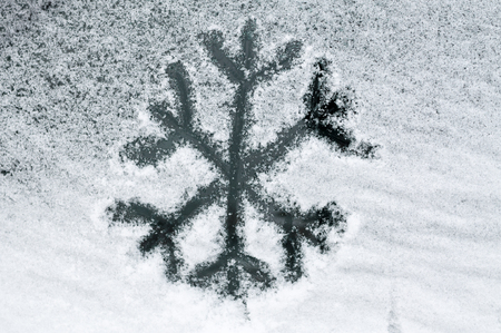 Snowflake drawn in snow on car windowの写真素材
