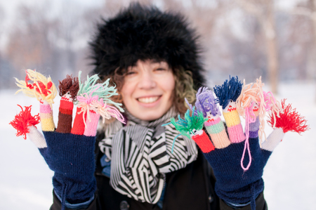 Young cute female wearing knitted colorful funny gloves in winterの写真素材