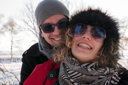 Man embracing young woman enjoying in beautiful sunny winter day Outdoors. Snow. Winter Vacation.の写真素材