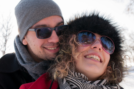 Man embracing young woman enjoying in beautiful sunny winter day Outdoors. Snow. Winter Vacation.の写真素材