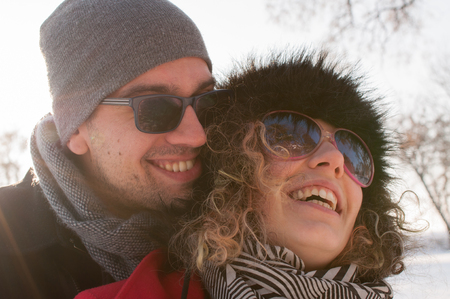 Man embracing young woman enjoying in beautiful sunny winter day Outdoors. Snow. Winter Vacation.の写真素材