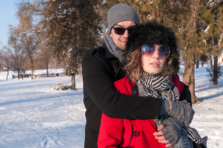Happy Couple enjoying in beautiful sunny winter day Outdoors. Snow. Winter Vacation.の写真素材