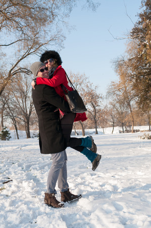 Young happy couple have fun on fresh snow at beautiful winter sunny day on vacationの写真素材