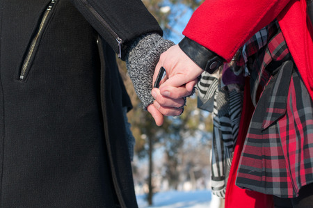 Young couple holding hands standing outdoors in winter, closeupの写真素材