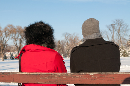 Couple Sitting On Bench In Winter, back viewの写真素材