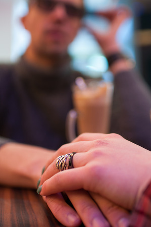 Young couple holding hands at the cafe, closeupの写真素材