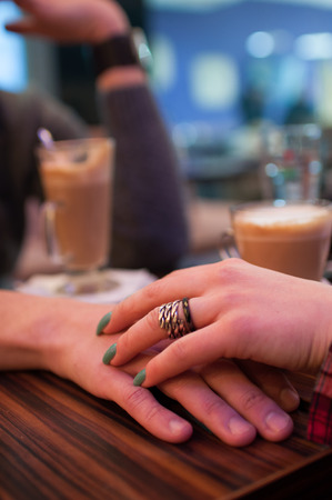 Young couple holding hands at the cafe, closeupの写真素材