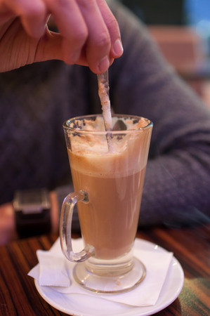 Close up of hand mixing coffee with a spoon in the cup.の写真素材