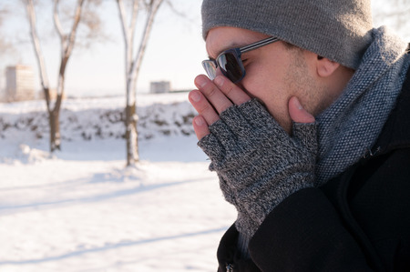 Man sneezing outdoors on the snow in winterの写真素材