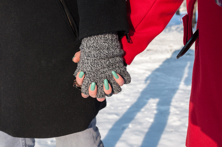 Young couple holding hands standing outdoors in winter, closeupの写真素材