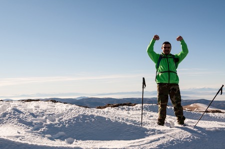 Hiker happy to conquer the mountain peak outstretching his armsの写真素材