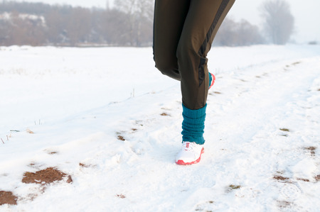 Woman running on a snowy country road, low section, front viewの写真素材
