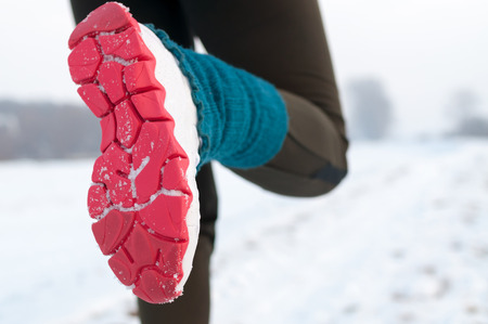 Closeup of female runner shoe running on snowの写真素材