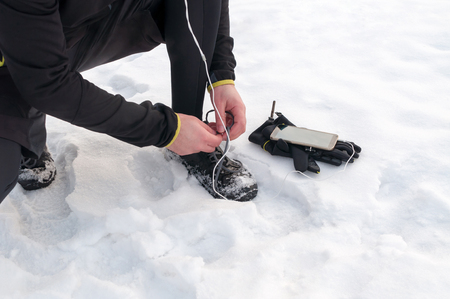 Young sport man tying running shoes during winter training outside in cold snow weatherの写真素材
