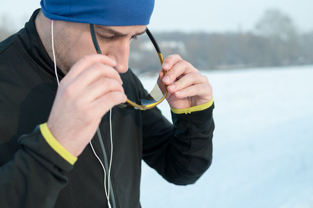 Healthy young man puts sport glasess outside on snow before running on winter dayの写真素材
