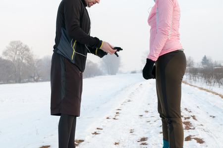 Man and woman warming up and preparing before running outside on snow on winter dayの写真素材