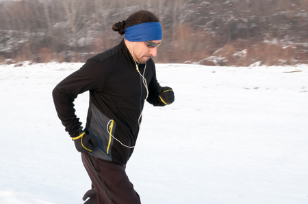 Male athlete running outdoor on cold winter day. Running, jogging, sport, fitness, active lifestyle concept, cold weather training. Motion blur.の写真素材