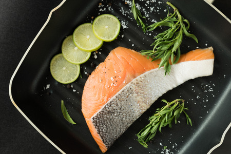 orange salmon with leather and lemon slices put in a grill pan that 
sprinkle by salt paper and taragon leafの写真素材