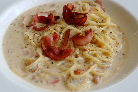 Spaghetti carbonara cream and egg sauce and topping bacon serve on white plateの写真素材