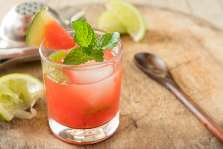 watermelon and vodka mix with 
peppermint on top in small glass with one of watermelon pice and squeeze the lemon set on chopping bordの写真素材