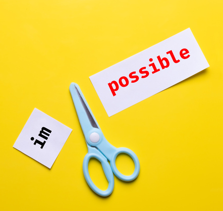 blue scissor cut white paper "impossible" to "possible" on yellow background. change to chance success concept.の写真素材