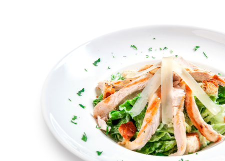 salad with chicken, croutons and greens (Caesar) on a plate on white backgroundの写真素材
