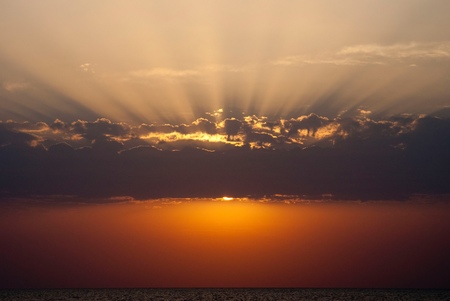 Golden sunrise with sunbeams in red seaの写真素材