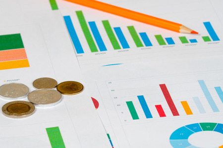 colorful pie and bar charts with coinsの写真素材