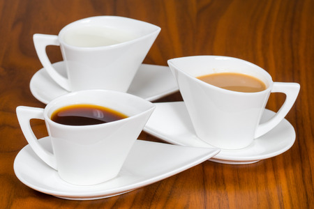 three white coffee cups on brown wooden tableの写真素材