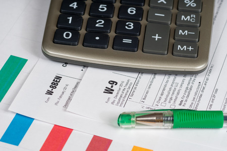 tax reporting forms with closed green pen and calculatorの写真素材