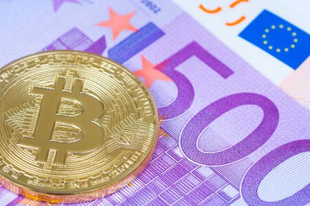 golden bitcoin metallic coin over euro banknotes close up shotの写真素材
