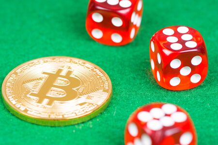 bitcoin metal coin with red dices on green clothの写真素材