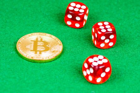 bitcoin metal coin with red dices on green clothの写真素材