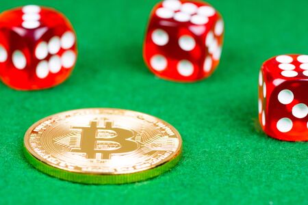 bitcoin metal coin with red dices on green clothの写真素材