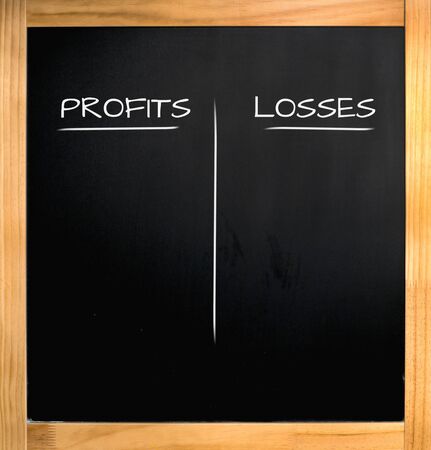 profits losses, chalk text on blackboard with wooden frameの写真素材