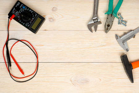 hand tools and multimeter on wooden planks