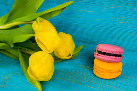 yellow tulips with macaroons on turquoise wooden tableの写真素材