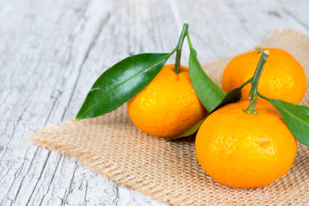 tangerines with leaves on jute napkinの写真素材