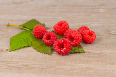 sweet juicy raspberry and green leaf on wooden tableの写真素材