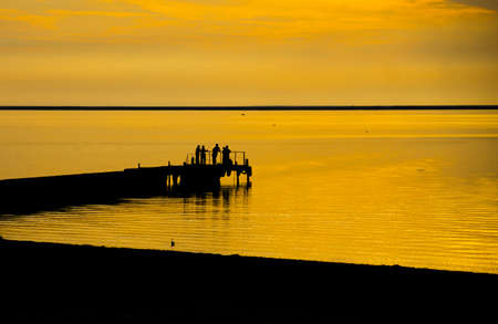 fisherfolk group in orange sunset light, outline shotの写真素材