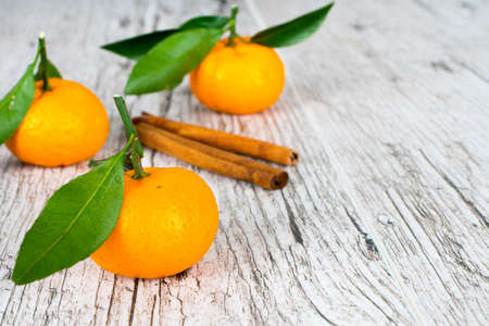 tangerines with leaves and cinnamon on wooden tableの写真素材