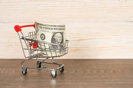 shopping cart with dollars banknotes over wooden backgroundの写真素材